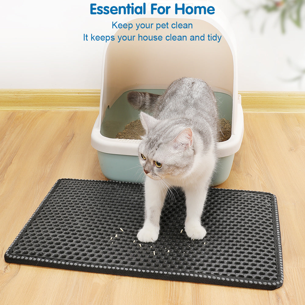 Gray cat stepping out of a litter box onto a black cat litter box mat on wooden floor